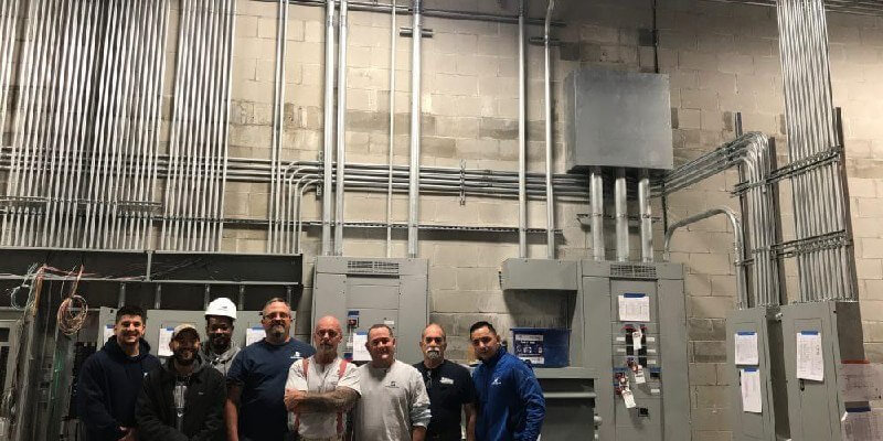 Bates Electric industrial team in front of panel